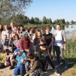 Dzieci ze Świetlicy środowiskowej pozują do zdjęcia na tle zbiornika wodnego Kępina