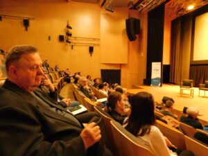 Widok gości konferencji siedzących w fotelach sali kinowej