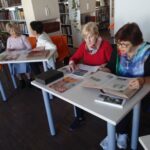 Seniorzy przeglądają pojedyncze egzemplarze książek historycznych