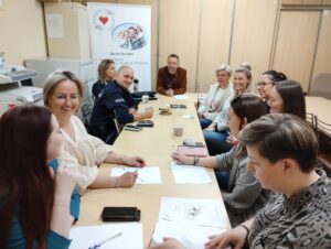 Pracownicy socjalni i dzielnicowi Komendy Powiatowej Policji siedzą przy stole w siedzibie Miejskiego Ośrodka Pomocy Społecznej Centrum Opieki Socjalnej w Zduńskiej Woli