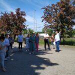 Seniorzy stoją przed przychodnią w Karsznicach dyrektor wskazuje ręką budynek