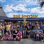 grupa osób stoi przed wejściem do ZOO