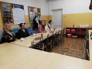 Panie studentki siedzą przy stolikach i słuchają prezentacji