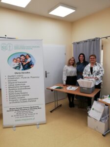 Trzy osoby stoją przy miejscu rejestracji