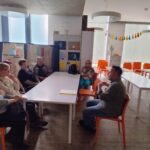 Seniorzy siedzą przy stolikach i słuchają prelekcji historycznej. PanTomasz Polkowski opowiada historię miasta Zduńska Wola