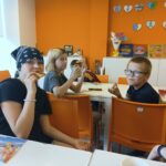 Dzieci siedzą przy stolikach i jedzą pizzę