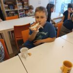 Chłopiec siedzi przy stoliku i je pizzę