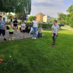 Chłopiec rzuca woreczkiem do obręczy, wychowawca liczy czas na stoperze, inne dzieci obserwują