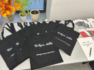 Zdjęcie przestawia torby bawełniane przeznaczone dla wszystkich uczestniczek projektu socjalnego z logo „Usłysz Siebie – odwaga zaczyna się od słów”