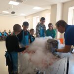 Dzieci stoją, biorą udział w doświadczeniu chemicznym