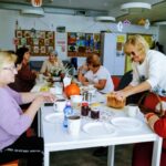 Zdjęcie Seniorek przy wspólnym stole, seniorka kroi chleb