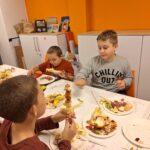 Chłopcy nabijają kawałki owoców na patyczki, robiąc szaszłyki