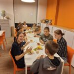 Dzieci siedzą przy stole, kroją owoce