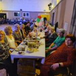 Seniorzy siedzą przy stołach