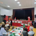 Seniorzy siedzą przy wspólnych stołach i słuchają przemowy kierownika Działu Zdrowia i Polityki Społecznej Urzędu Miasta Zduńska Wola panią Katarzynę Balzam