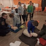 Dzieci wykonują resuscytacje na fantomie, inne dzieci się przyglądają
