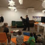 Funkcjonariusze pokazują jak pomóc osobie krztuszącej się